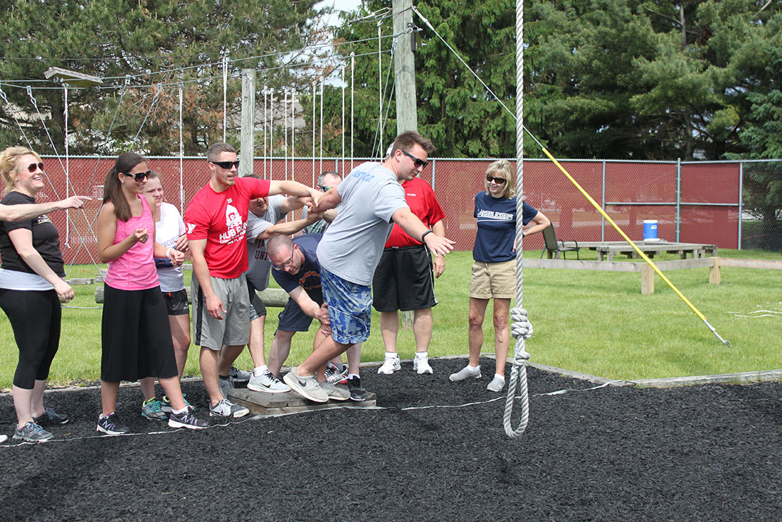 A local business group navigates a Beyond Boundaries Challenge Course obstacle.